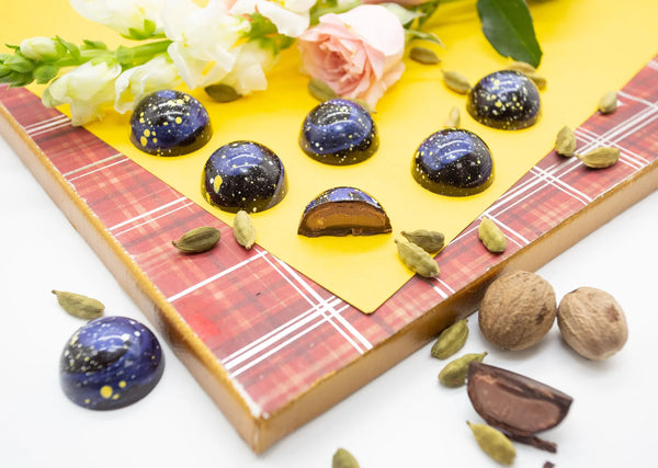 Cardamom Galaxy dome-shaped chocolate bonbons with blue and dark blue coloring and yellow speckles like stars in the sky