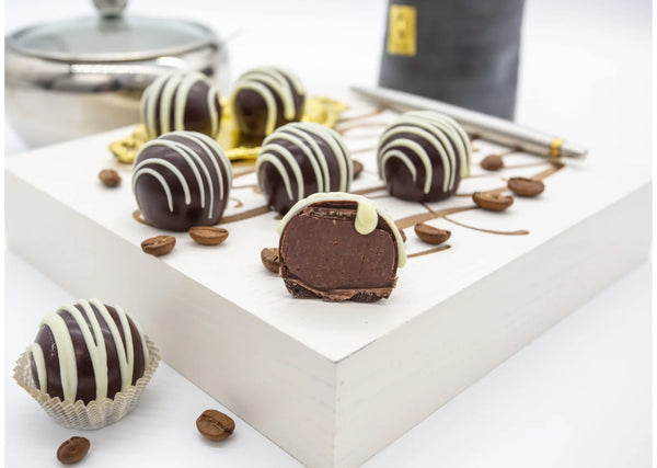 Coffee Shot Truffles with extra dark shell and coffee infused creamy ganache, topped with white chocolate decorative stripes on a white table