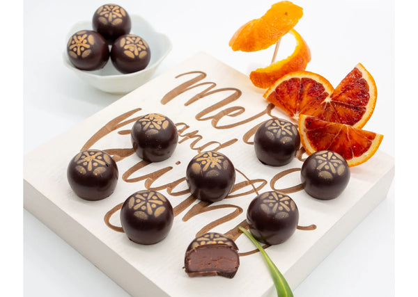 8 Zesty Orange Dark Chocolate Truffles with slices of blood orange on a white table