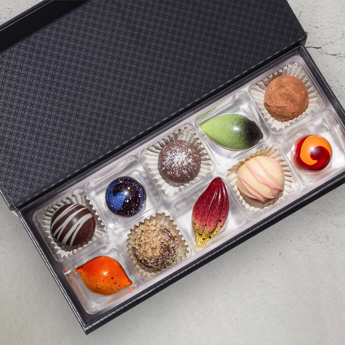 10 creamy and spiced truffles and chocolate bonbons part of Silk Road Luxury Box in front of a closed gift box