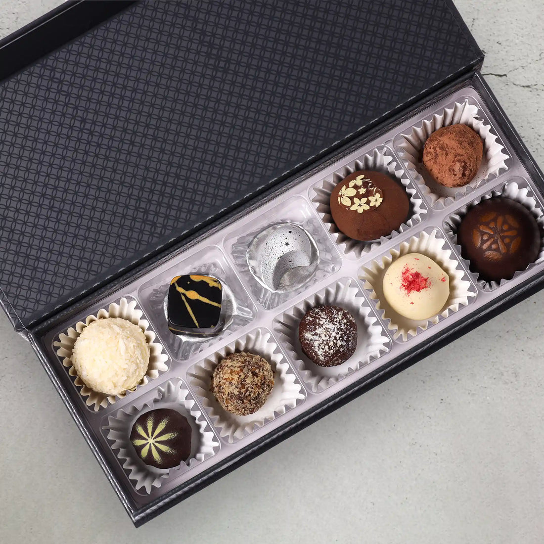 10 truffles and creamy chocolates part of the Velour Luxury Gift Box in front of a closed gift box