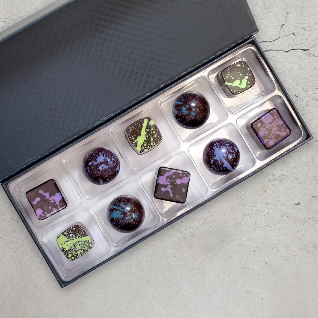 10-Piece Elite Collection Gift Box with custom assortment of dark chocolate bonbons splattered with green, blue, and purple