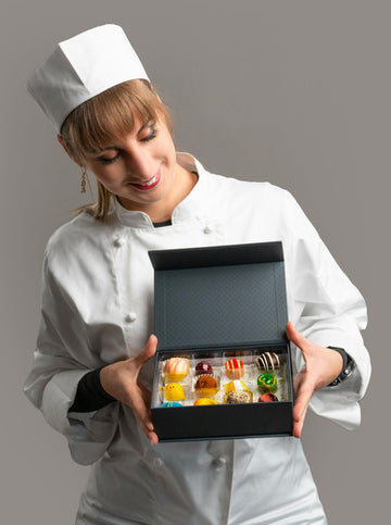 Beata in chef uniform holding luxury box of sugar free healthy chocolates