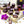 Cardamom Lava dark chocolate bonbons with purple splattered paint and creamy cardamom filling on a white table surrounded by purple and white flowers and cardamom pods