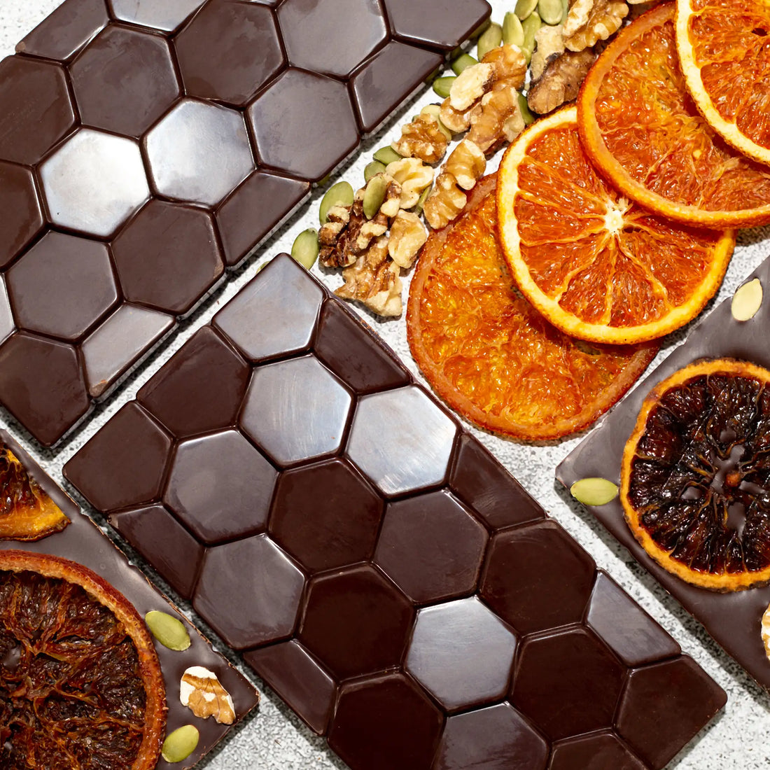 Happiness Dark Chocolate Bar with the front showing a hexagon pattern and the back with caramelized oranges, walnuts, and pumpkin seeds