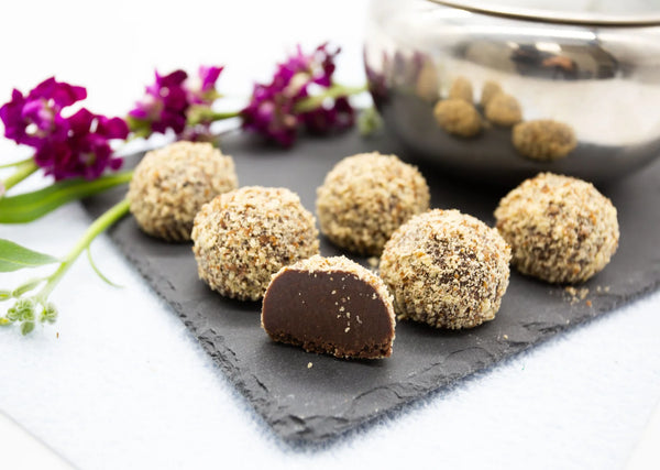 Nutty Lavender Truffles with rich milk chocolate ganache and coated with walnut pieces on a table next to lavender flowers