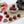 Raspberry Rose deep red dark chocolate bonbons with pink raspberry filling on a white table with pink roses, a teapot, and raspberries